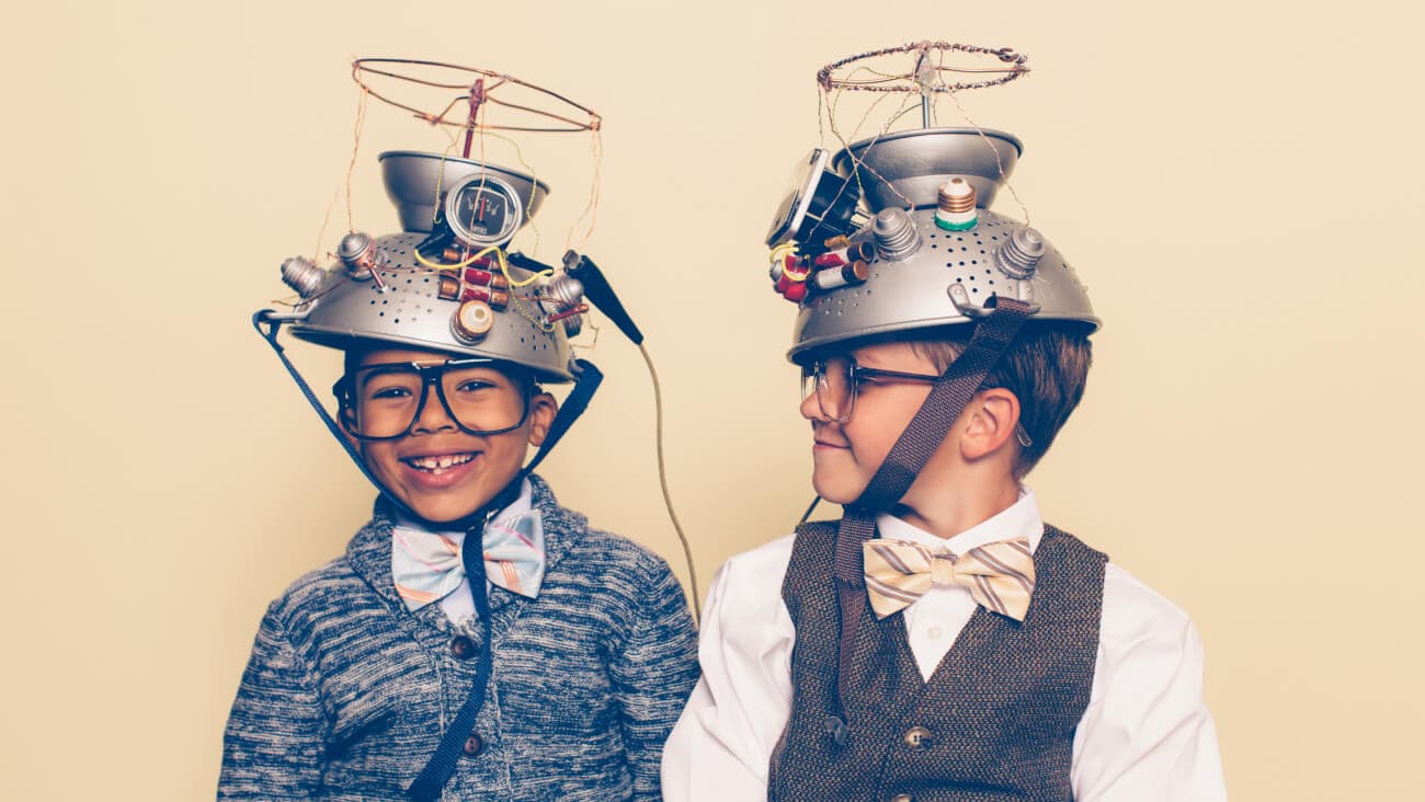 two young boys looking professorial, wearing bow ties, vests and home-made mind reading helmets made from colanders.